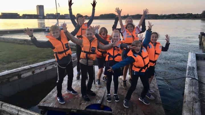 En flok glade juniorspejdere på en tømmerflåde de har bygget til et spejdermøde