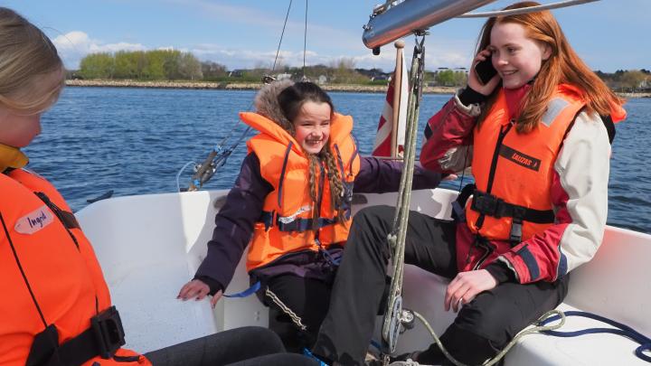 En minispejder sidder med roret i en jolle.